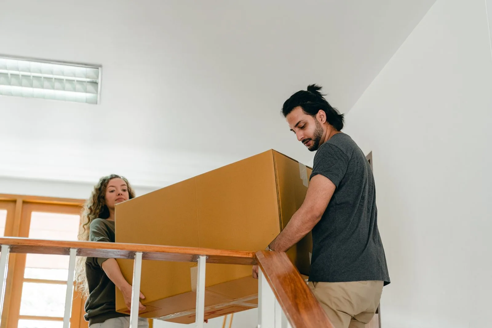 Two people carrying a large packed cardboard carton together on moving day
