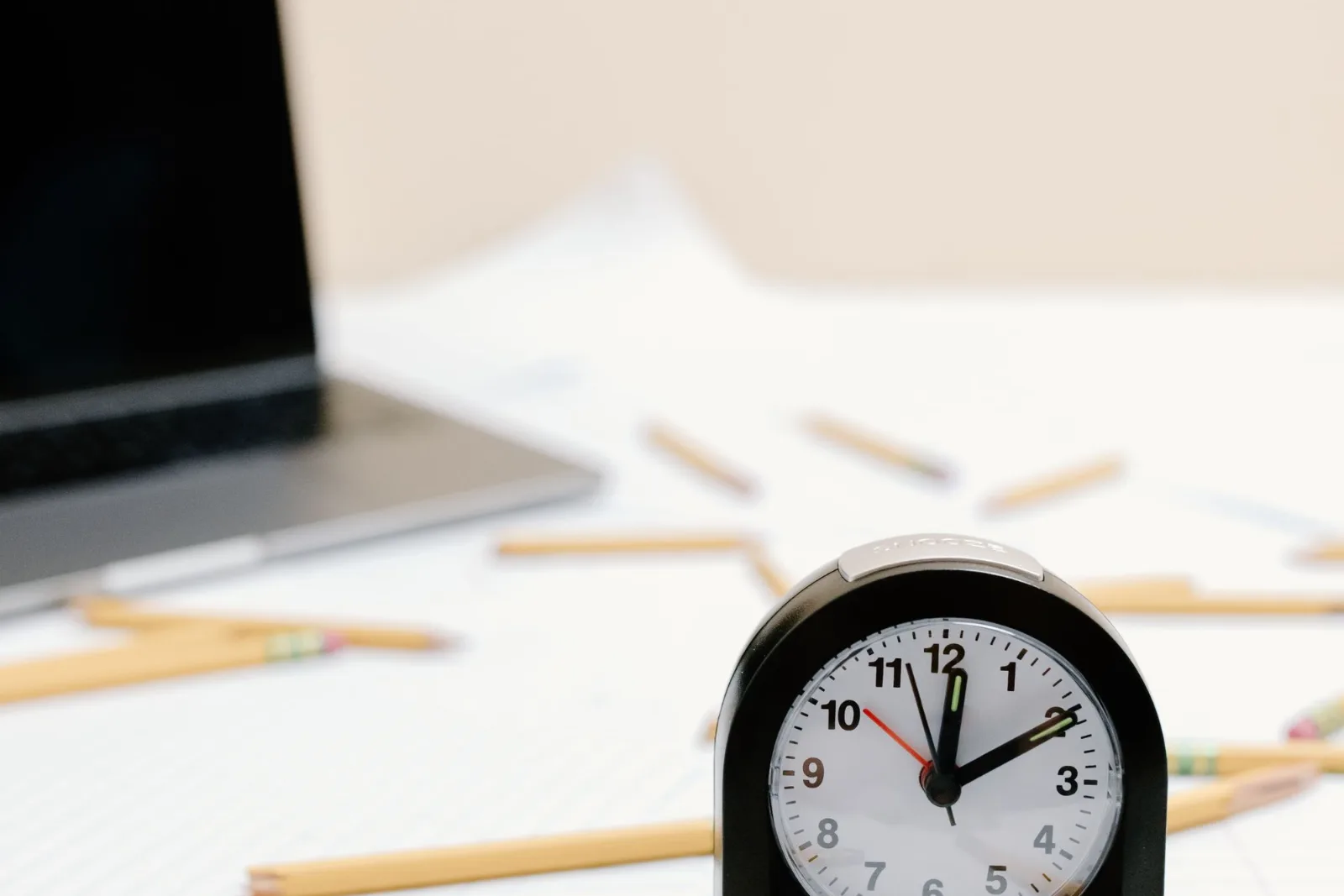 A clock resting on scattered papers and pencils