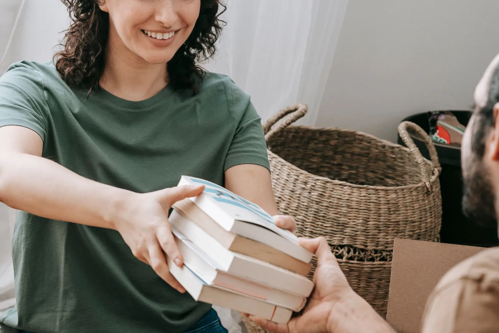 Two people packing books into cardboard boxes together indoors