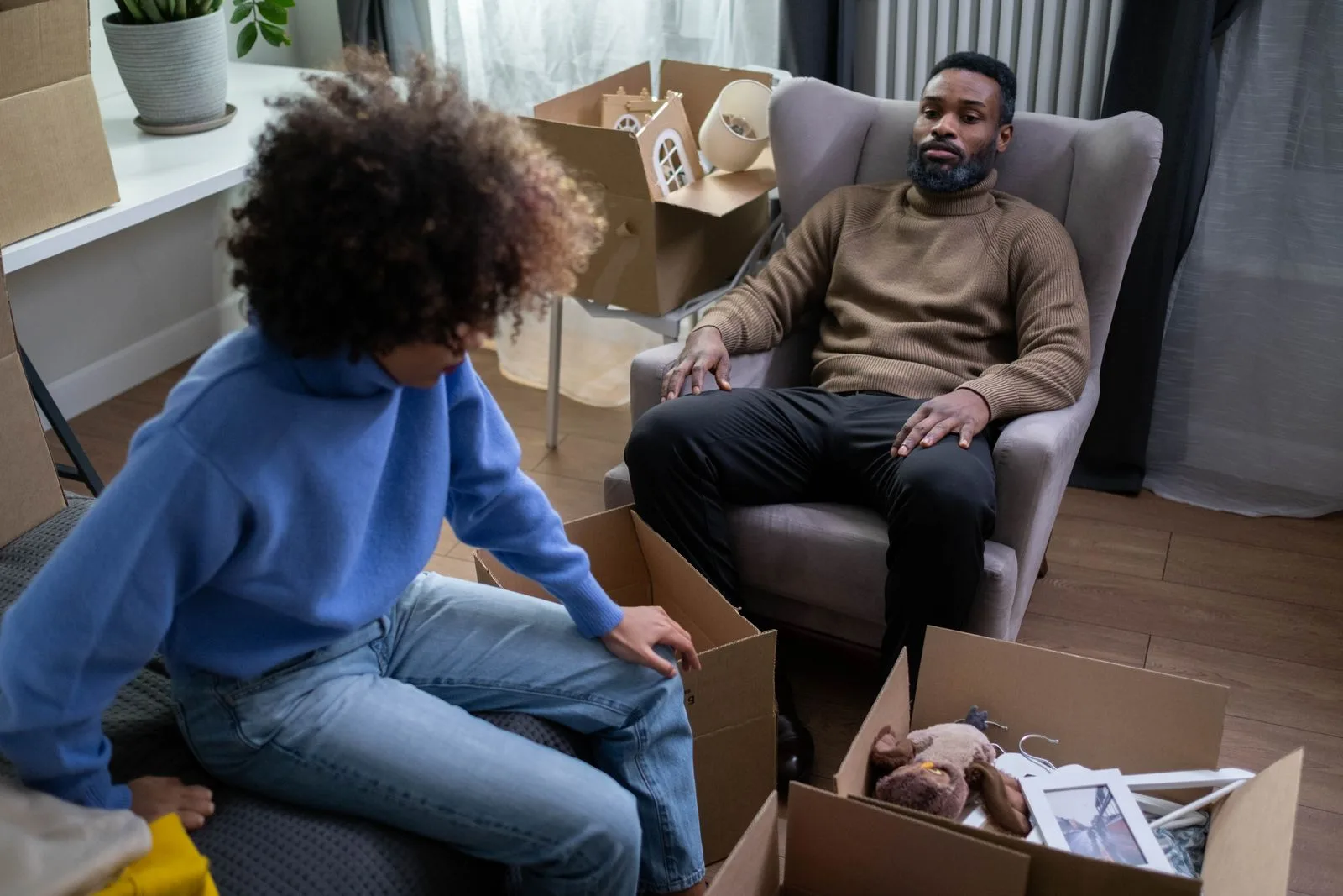 A couple packing cardboard boxes in a living room during a move