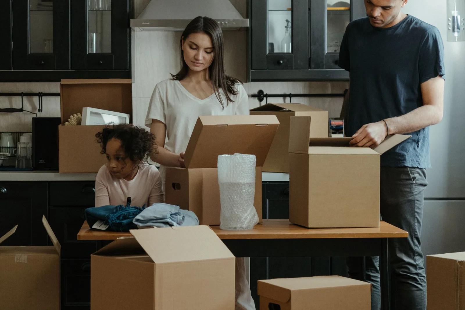 A family unpacking moving boxes together in a modern kitchen