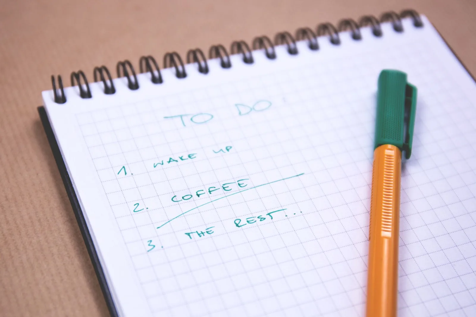 A handwritten to-do list on graph paper with a pen resting on it