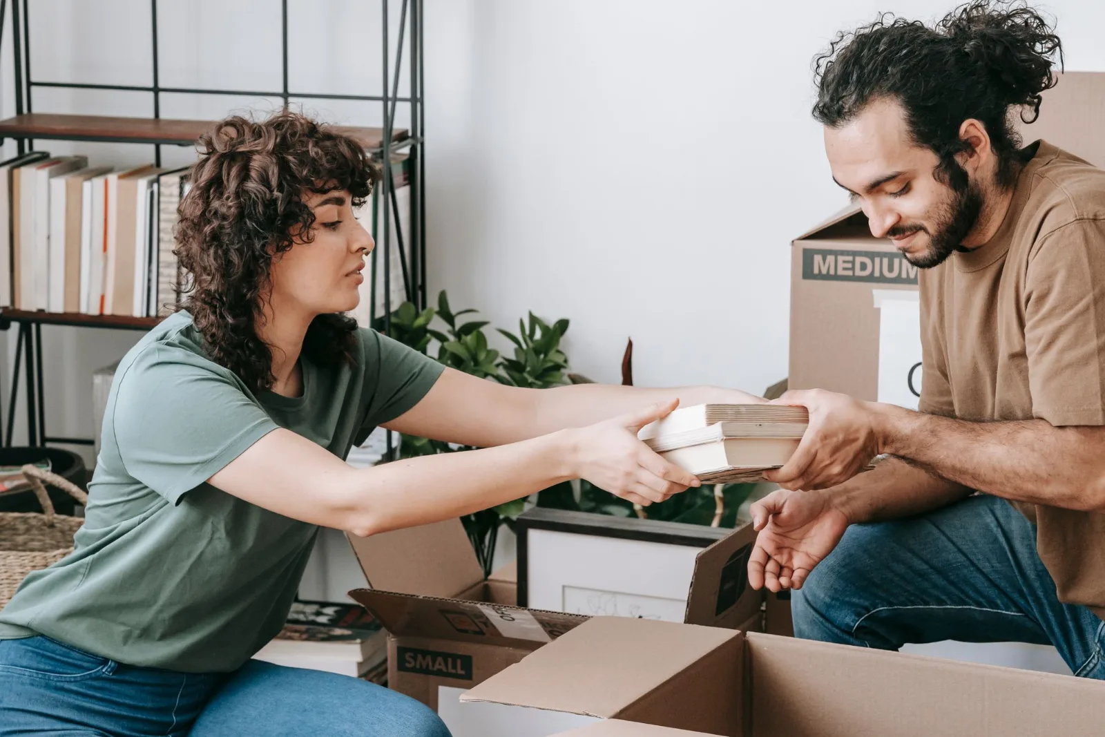 Two people packing books into boxes in their home before relocating
