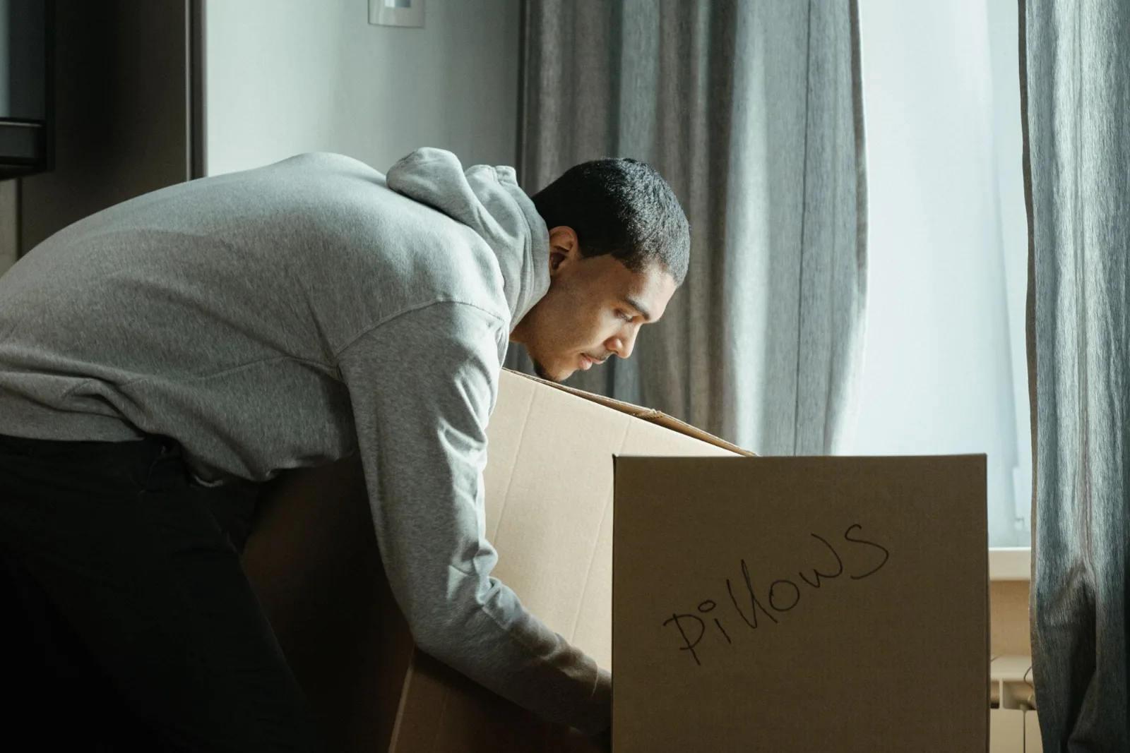 A young man packing cardboard cartons in an apartment during a move