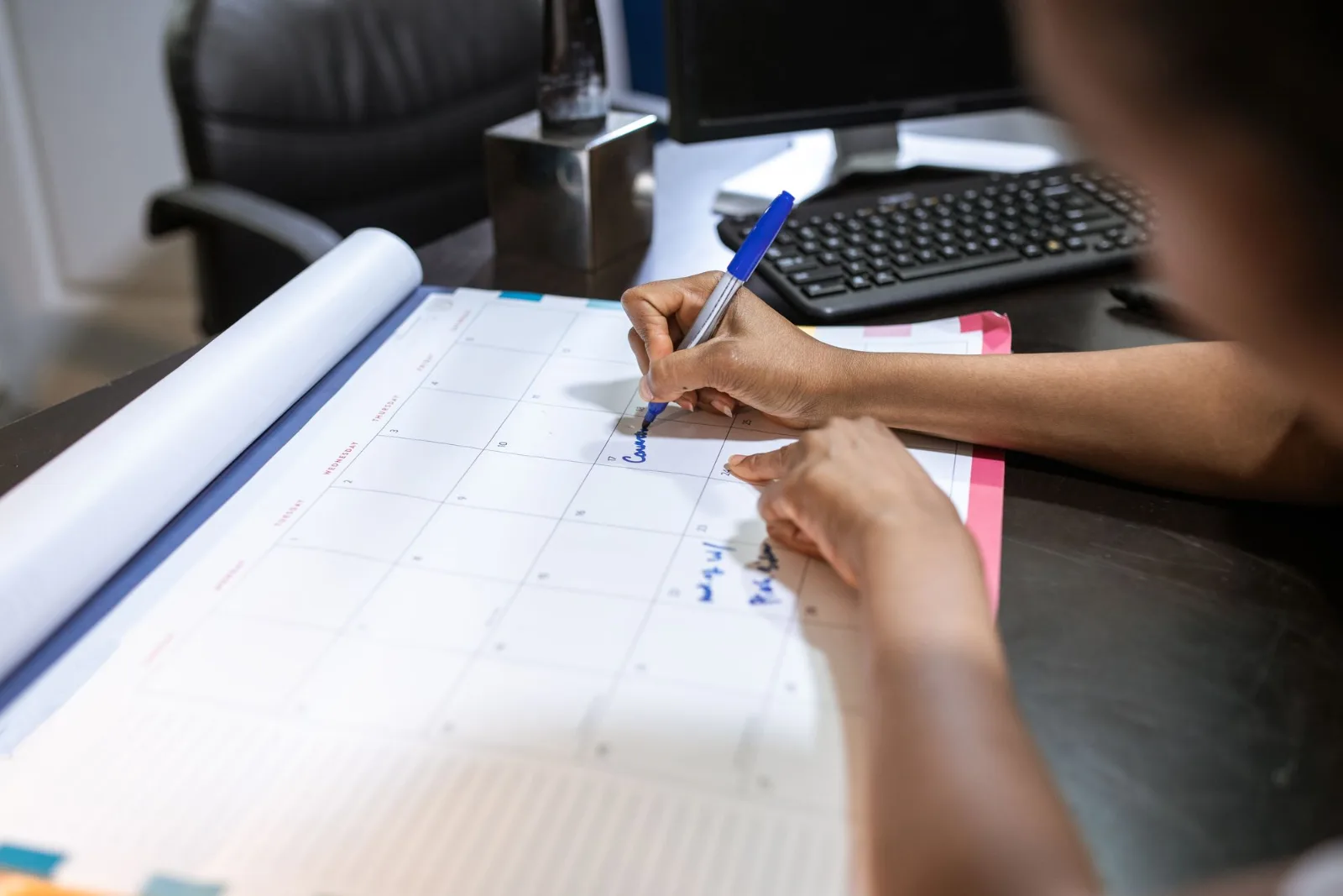 A woman planning her schedule on a desk calendar