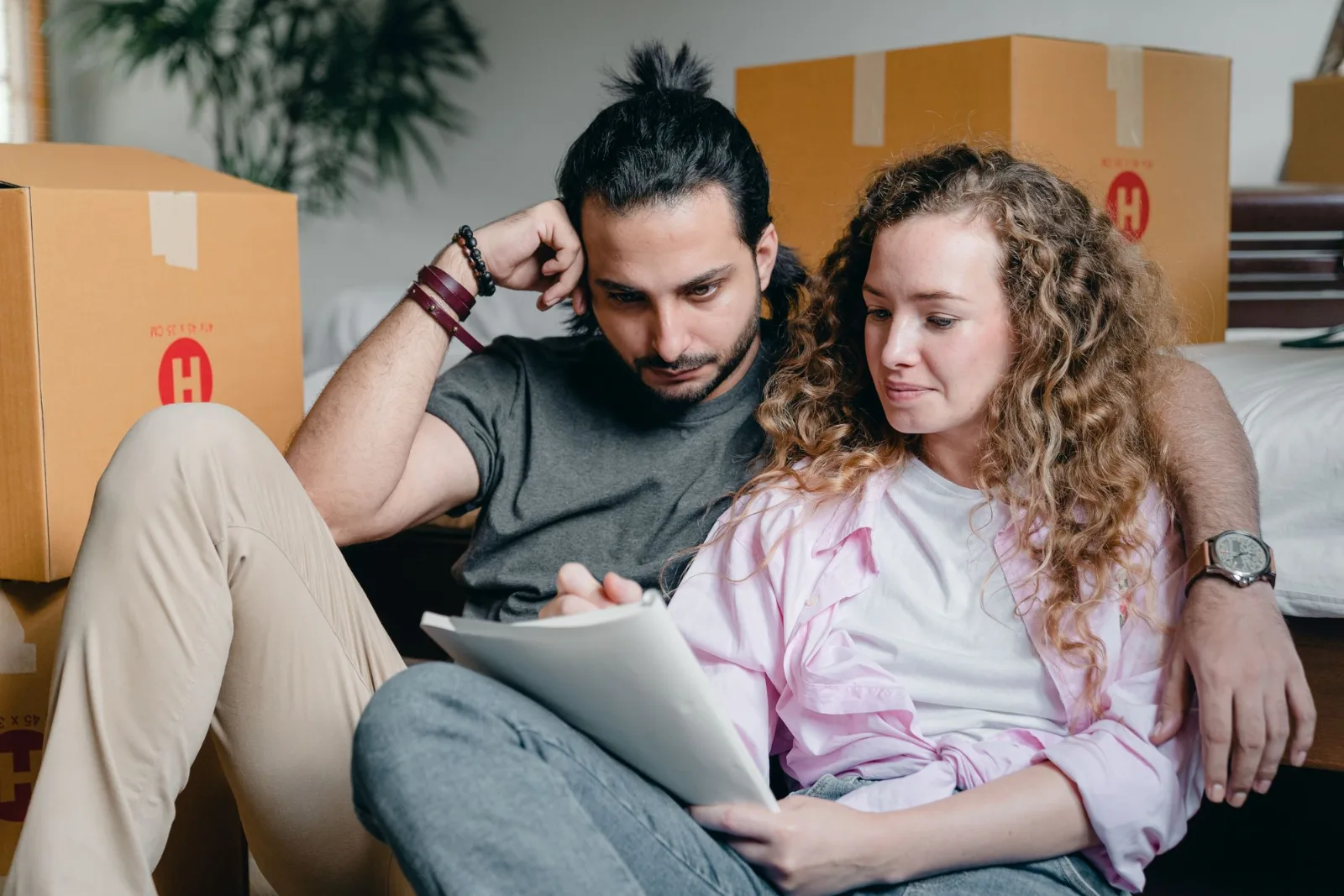 Two people sitting among packed cartons writing notes and working out a plan