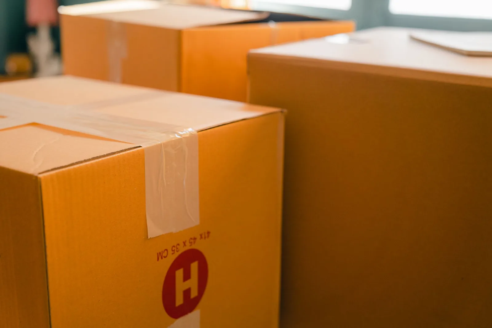 Cardboard containers sealed with tape placed near a window on a sunny day