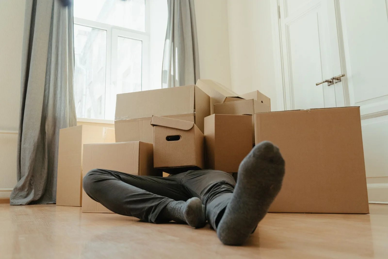 A person resting among cardboard boxes in a bright room after a long day of packing