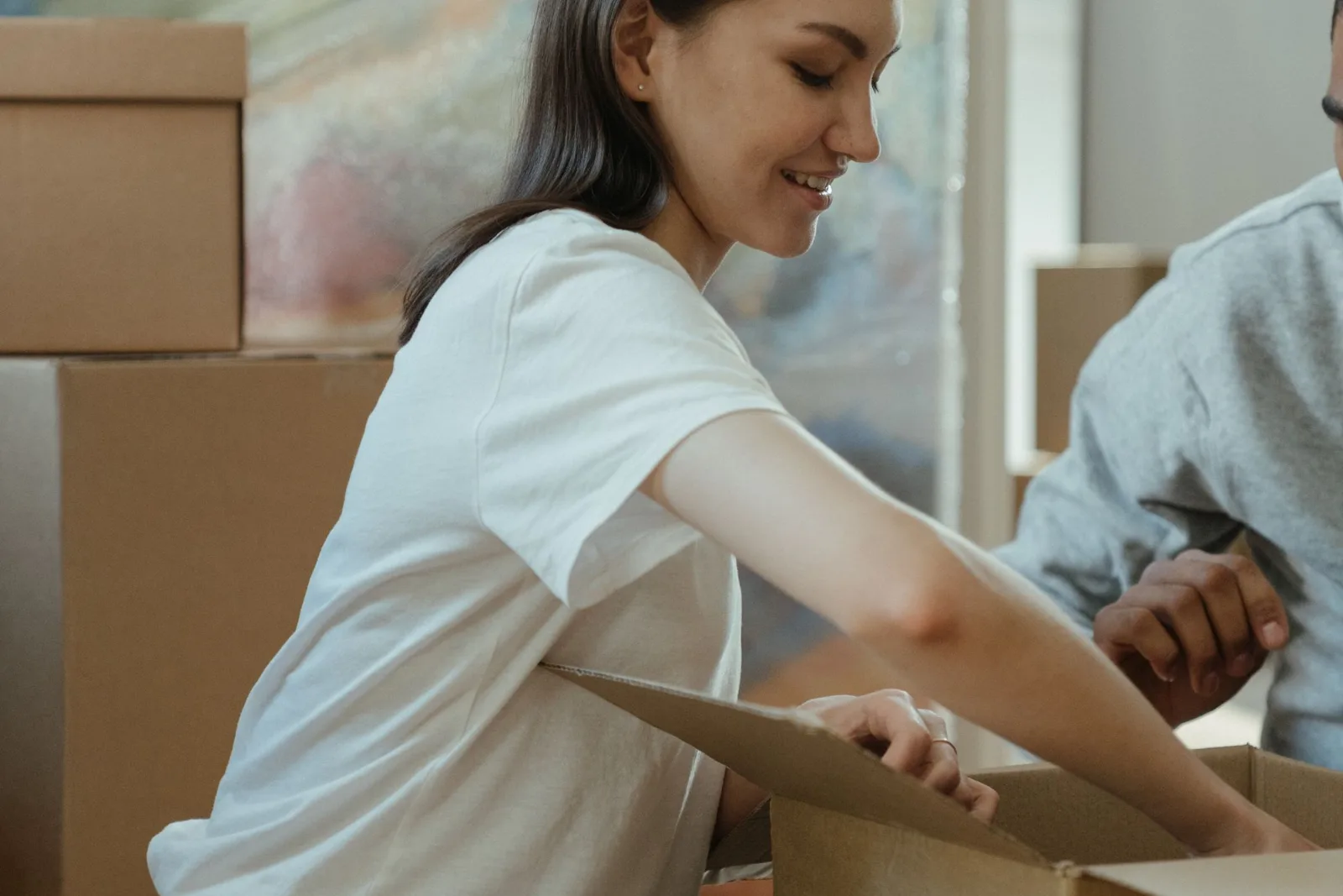 A woman unpacking cardboard boxes in the living room of a new home