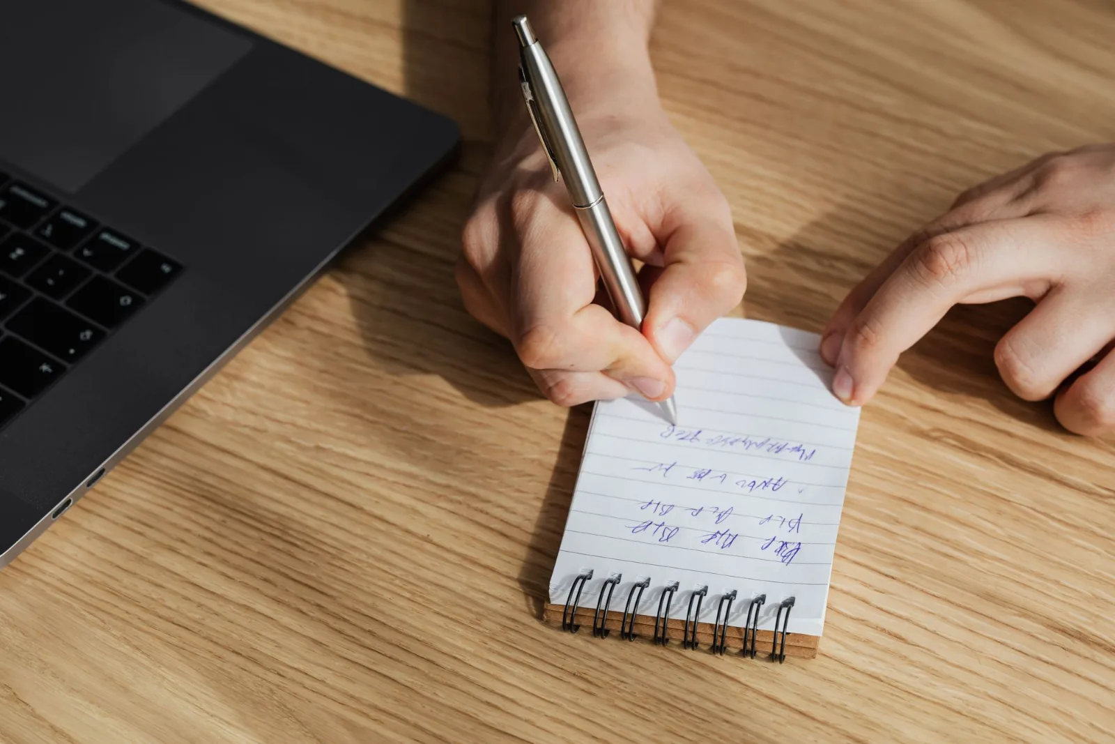A person writing notes in a spiral notebook while planning